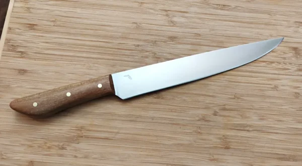 Right view of 9 1/4" Florida Pecan Carving Knife, 14" long, with a brushed drop point blade and pecan handle on wood.
