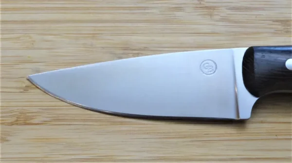 Left side of blade for a Goldilocks Knife showcasing the drop-point blade, on wooden surface