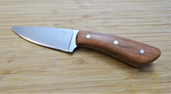 Wild Black Cherry Goldilocks #211 drop point EDC knife, full left view, 1095 steel blade, wild black cherry wood handle on wooden surface