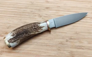 Custom elk antler knife with brushed drop point blade, brass fingerguard, and threaded pummel, right side view