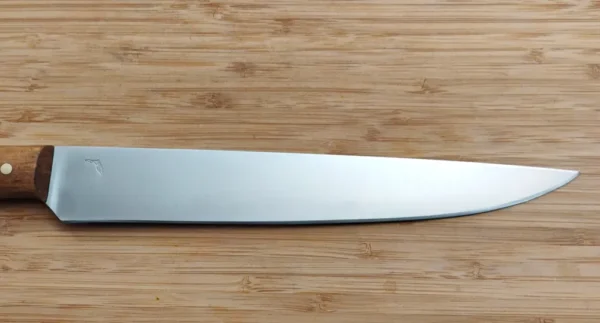Right close-up of 9 1/4" brushed drop point blade on Florida Pecan Carving Knife, made of 15N20 steel, on wood.