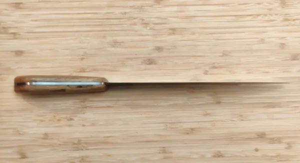 Belly view of Florida pecan handle on Florida Pecan Carving Knife with brass pins, on a wooden surface.