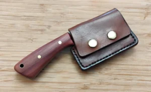 Mini-cleaver in leather sheath displaying Red Cedar handle and snap sheath