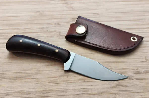 Upswept Clip Point Neck Knife with kingwood handle next to custom leather snap sheath.