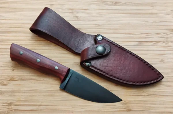 Red Cedar knife sitting next to snap sheath on a wooden background