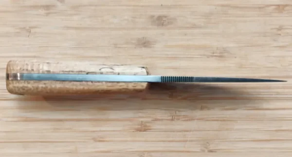 Spine view of the GreBec Drop Point 3-Finger Skinner, showing the 5/32-inch thick 1095 steel blade and thumb serrations