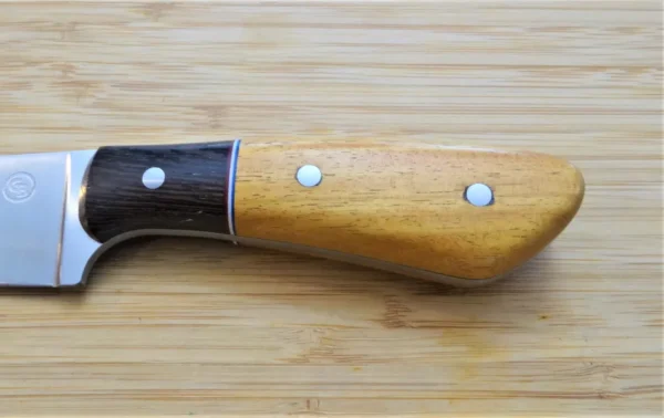 Left side of Osage Orange and Wenge Knife handle with mild steel pins on wooden surface.