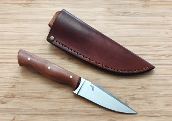 Wild Black Cherry Harpoon Clip Point #343 knife next to custom leather pouch sheath on wooden surface