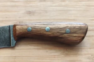Closeup of the left handle on a knife made from Bur Oak with mild steel pins.