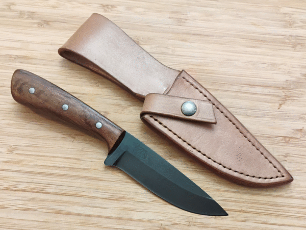 Live Oak Drop Point hunting knife next to its matching Live Oak bark-dyed leather sheath on a wooden surface