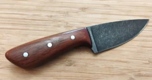 Right side of custom Cherry 3 Finger Skinner #362 knife featuring stabilized wood handle and mild steel pins on a wooden background